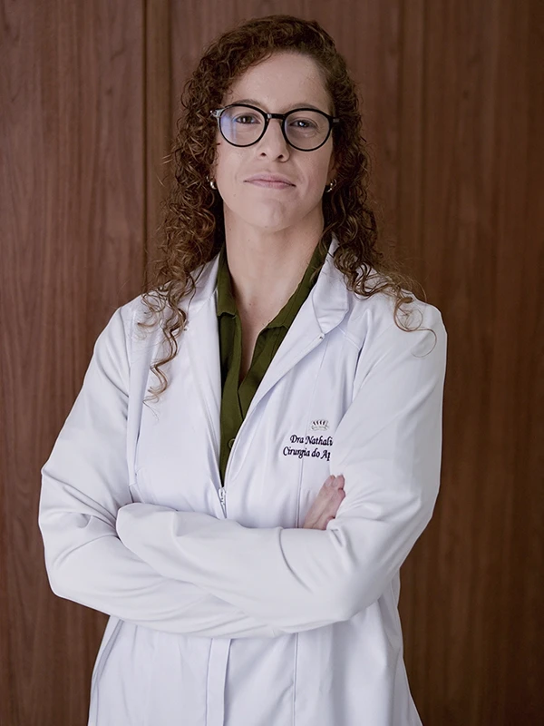 Dra. Nathalia Julio, cirurgiã do aparelho digestivo, de jaleco, em postura confiante